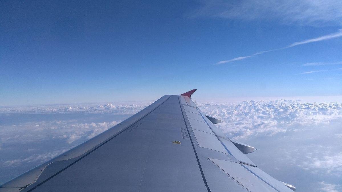 An aircraft wing above the clouds, seen from a passenger window