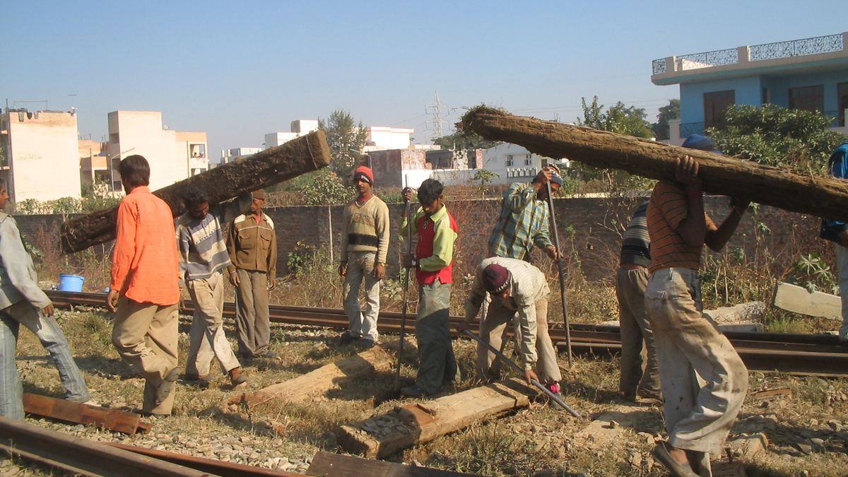 Indian Railways workers carrying sleepers during track maintenance