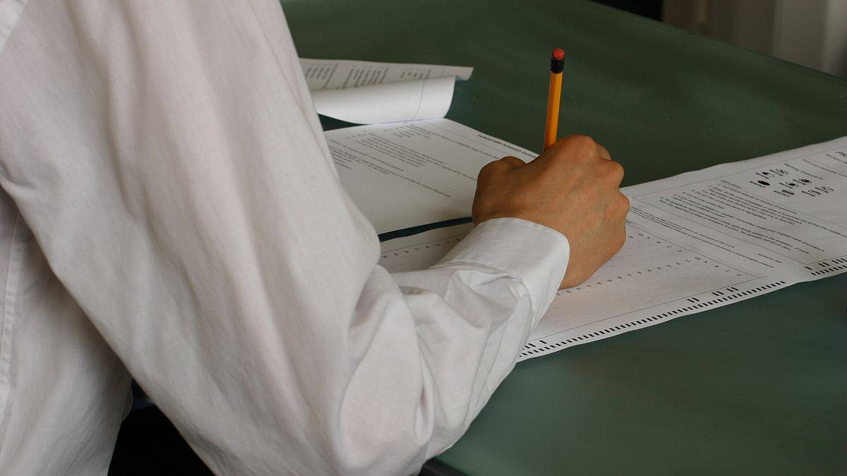 A candidate filling in an answer sheet in an exam hall